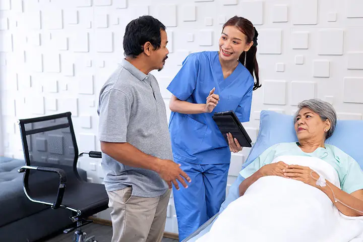 A husband visiting his wife in a care facility, both smiling and engaging in a conversation